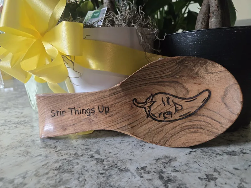 Wooden spoon rest engraved with a smiling chili pepper and the words Stir Things Up